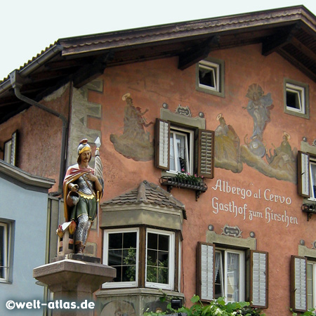 Gasthof mit wunderschöner Fassade am Tinneplatz im historischen Zentrum des mittelalterlichen Ortes Klausen im Eisacktal bei Brixen, davor der Brunnen mit St. Florian