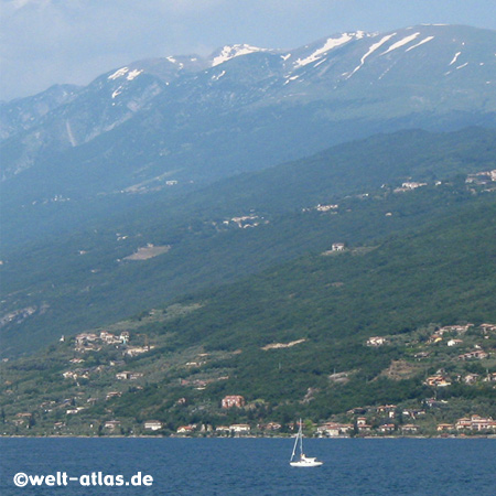 Ufer des Gardasees mit schneebedeckten Bergen im Hintergrund