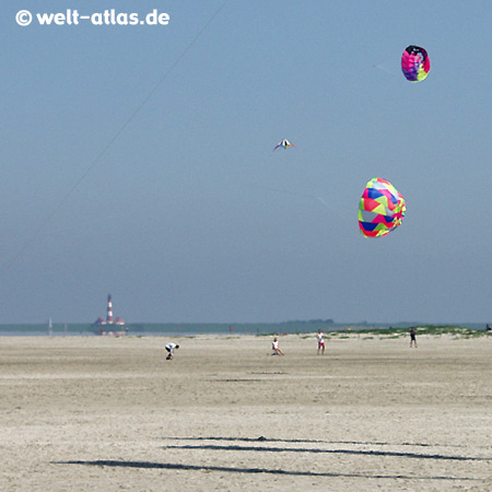 St. Peter-Ording, Kites am Strand, in der Ferne liegt der Westerhever Leuchtturm, dieser Strand ist die größte Sandkiste der Welt 