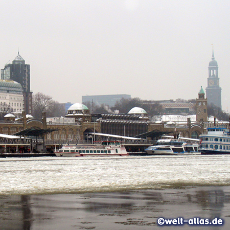 Die St. Pauli-Landungsbrücken an einem eisigen Wintertag, dahinter der Michel, Hamburg