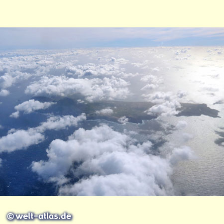 Beim Landeanflug auf Madeira kann man zwischen den Wolken einen Blick auf Madeiras kleine Schwester, die Insel Porto Santo werfen