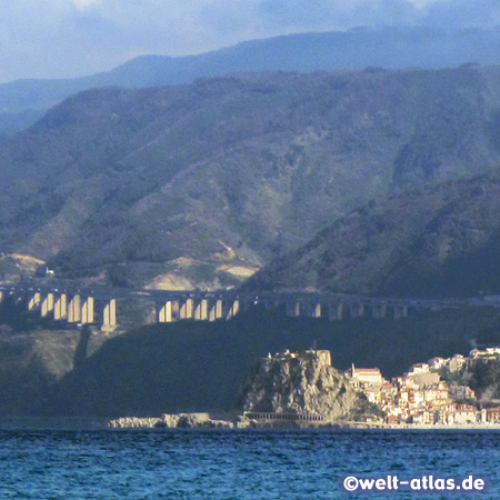 Blick vom Capo Peloro auf Sizilien über die Straße von Messina hinüber nach Scilla mit dem Castello Ruffo in Kalabrien, dahinter die Berge und als Hochstraße die Autostrada Salerno-Reggio Calabria