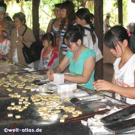 Hier im Mekong-Delta auf Unicorn Island werden die suessen Kokosnussbonbons von Hand hergestellt und mit Esspapier umwickelt 