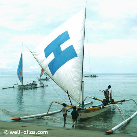 Sailing boat on beach, children are playing at the boat